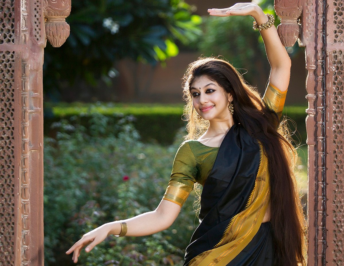 Dakshina dancing in a garden in a black and green sari